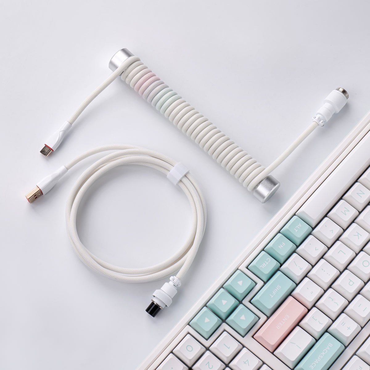 Pink-blue mixed coiled keyboard cable with silver guide bar beside a keyboard