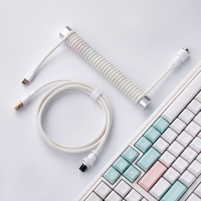 Pink-blue mixed coiled keyboard cable with silver guide bar beside a keyboard